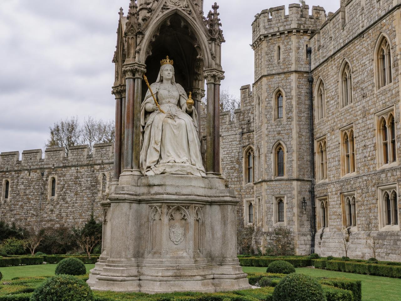 The stone statue of Queen Victoria seated beneath a Gothic canopy